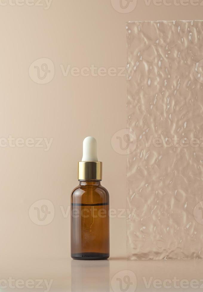 ein Gesichtsserum oder ätherisches Öl in einer braunen Tropfflasche, die auf beigem Hintergrund steht foto