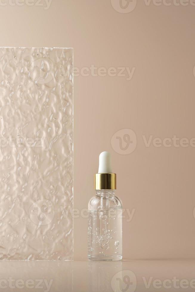 ein transparentes Gesichtsserum in Tropfflasche oder ätherisches Öl oder Gel auf beigem Hintergrund foto