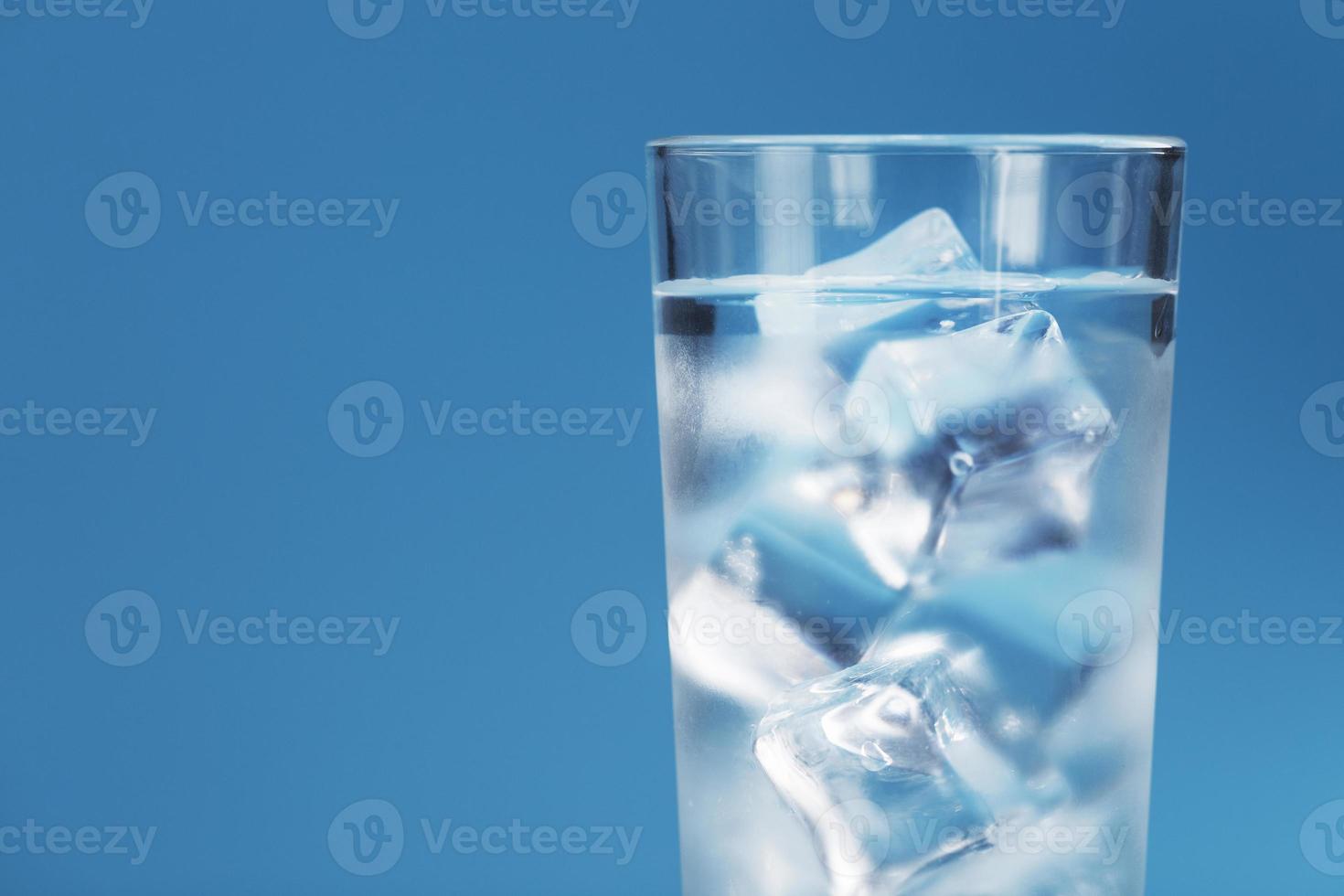 Glas mit Wasser und Eiswürfeln auf blauem Grund foto