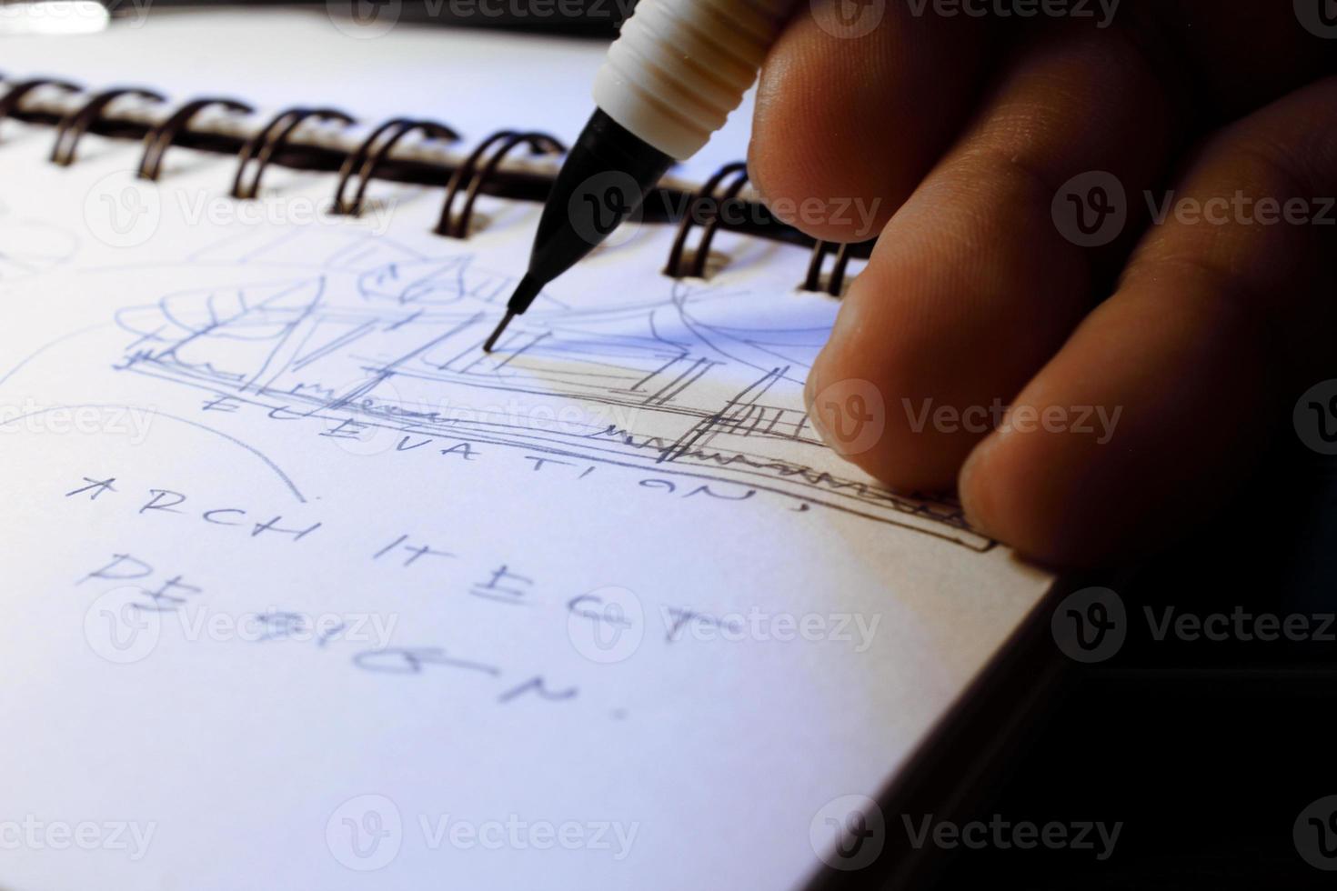 Die Hände des Architekten skizzieren Architekturpläne mit Bleistiften auf einem Skizzenbuch auf einem Schreibtisch mit einem Laptop. foto