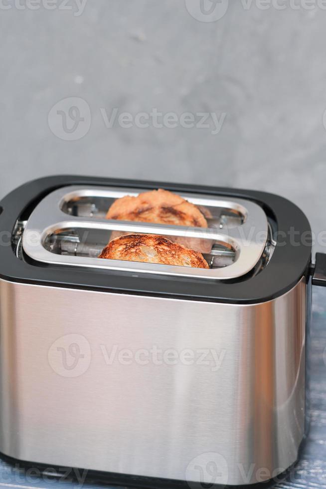 Zwei geröstete knusprige Brotstücke auf Toaster auf grauem Tisch, vertikal. foto