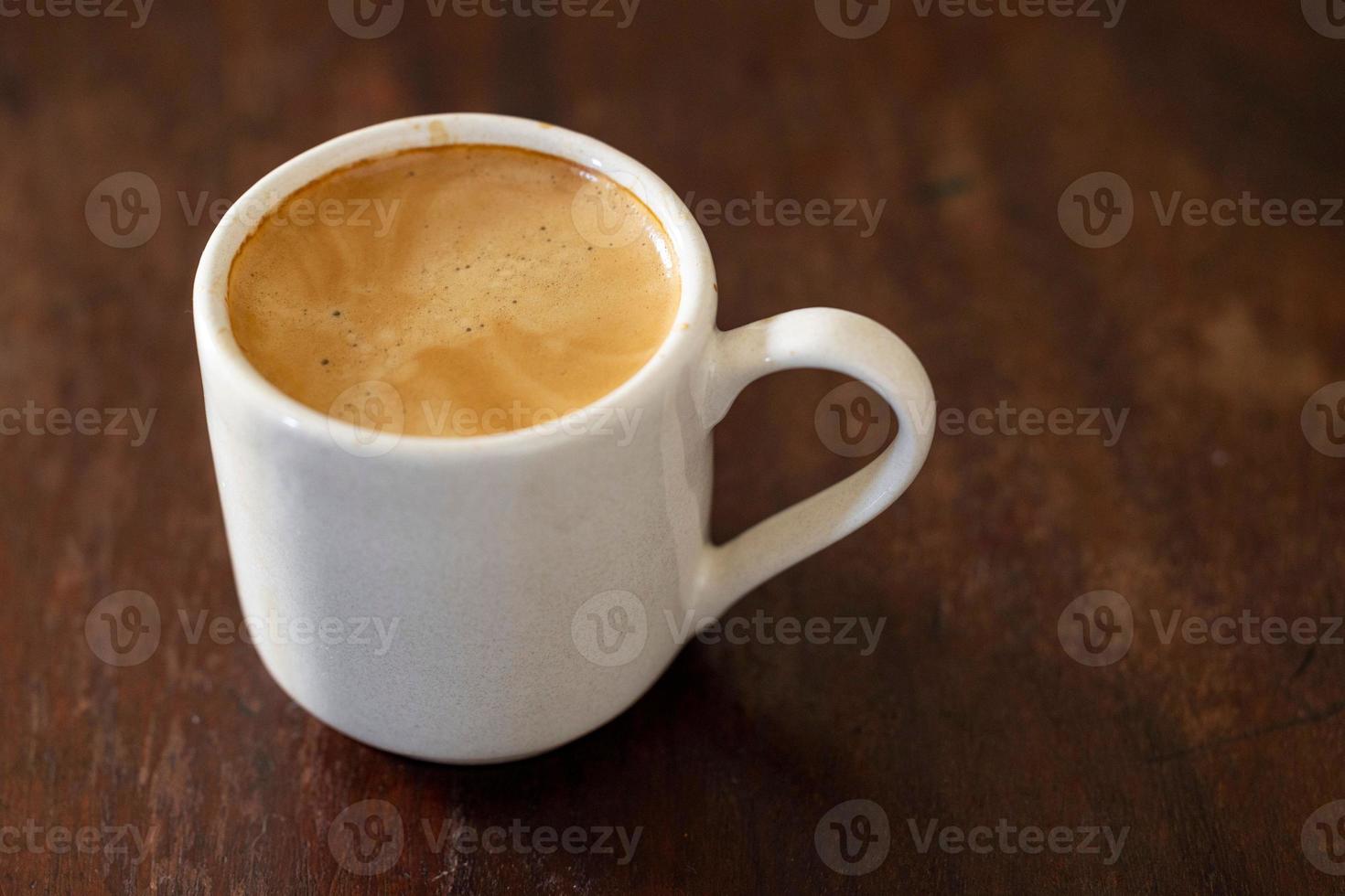 Tasse köstlichen Kaffee isoliert auf einem hölzernen Hintergrund foto