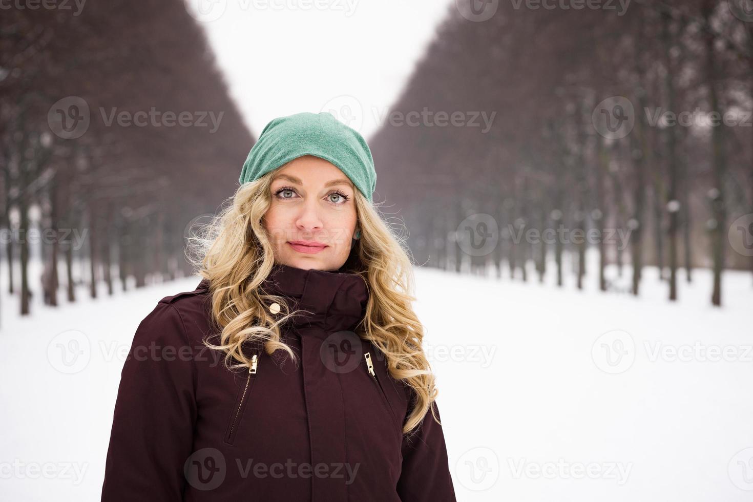 Frau mit warmer Winterkleidung in schneebedeckter Gasse foto