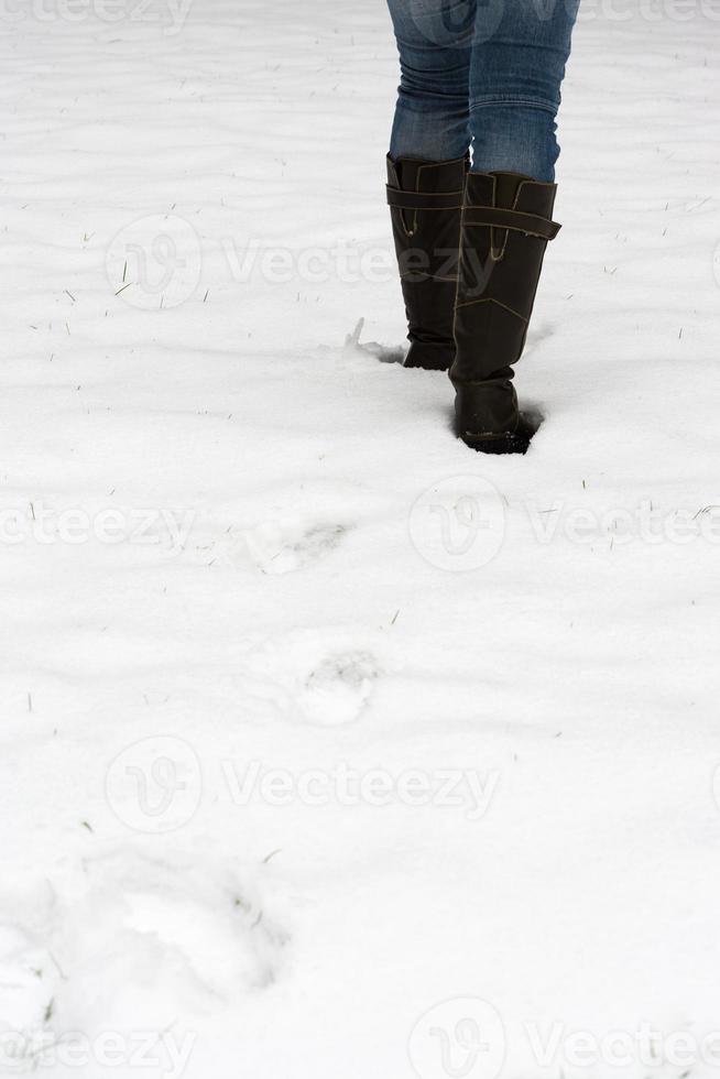 weibliche beine in stiefeln, die durch frischen schnee laufen foto