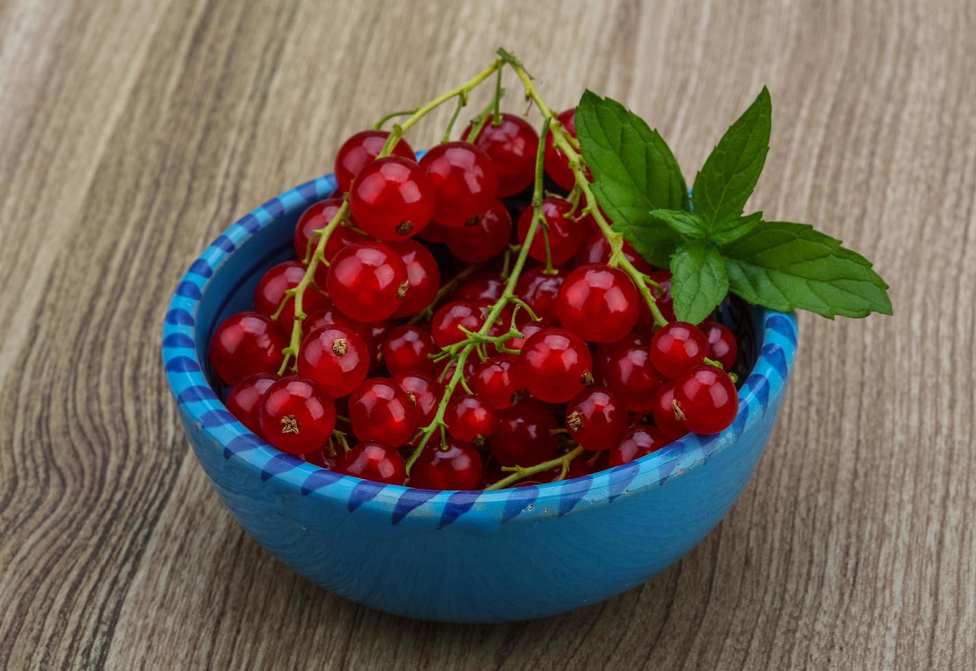 Rote Johannisbeeren in einer Schüssel auf Holzhintergrund foto