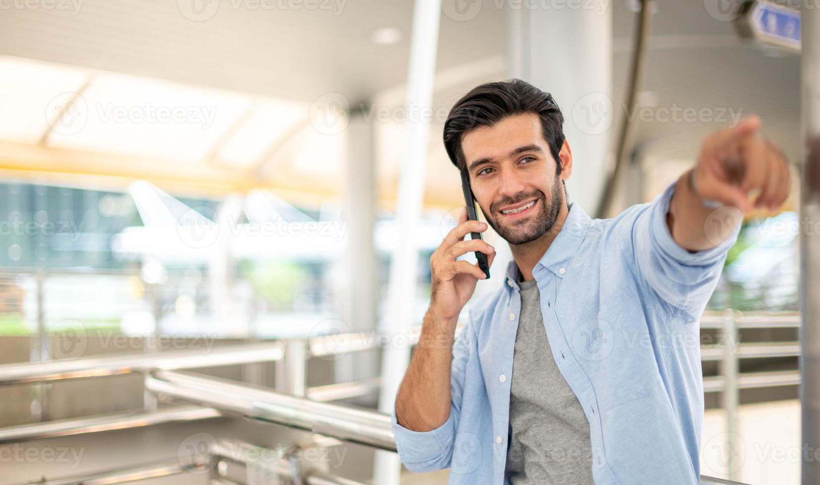 geschäftsmann, der auf etwas zeigt, während er ein smartphone verwendet, um mit seinem freund im freien zu sprechen foto