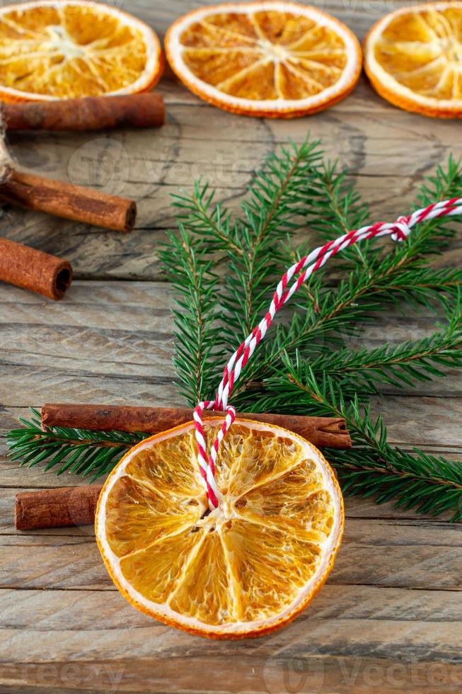 handgemachte natürliche weihnachtsdekorationen. Girlande und Tannenbaumspielzeug aus getrockneten Orangenscheiben auf Holztisch. winterstillleben komposition. foto