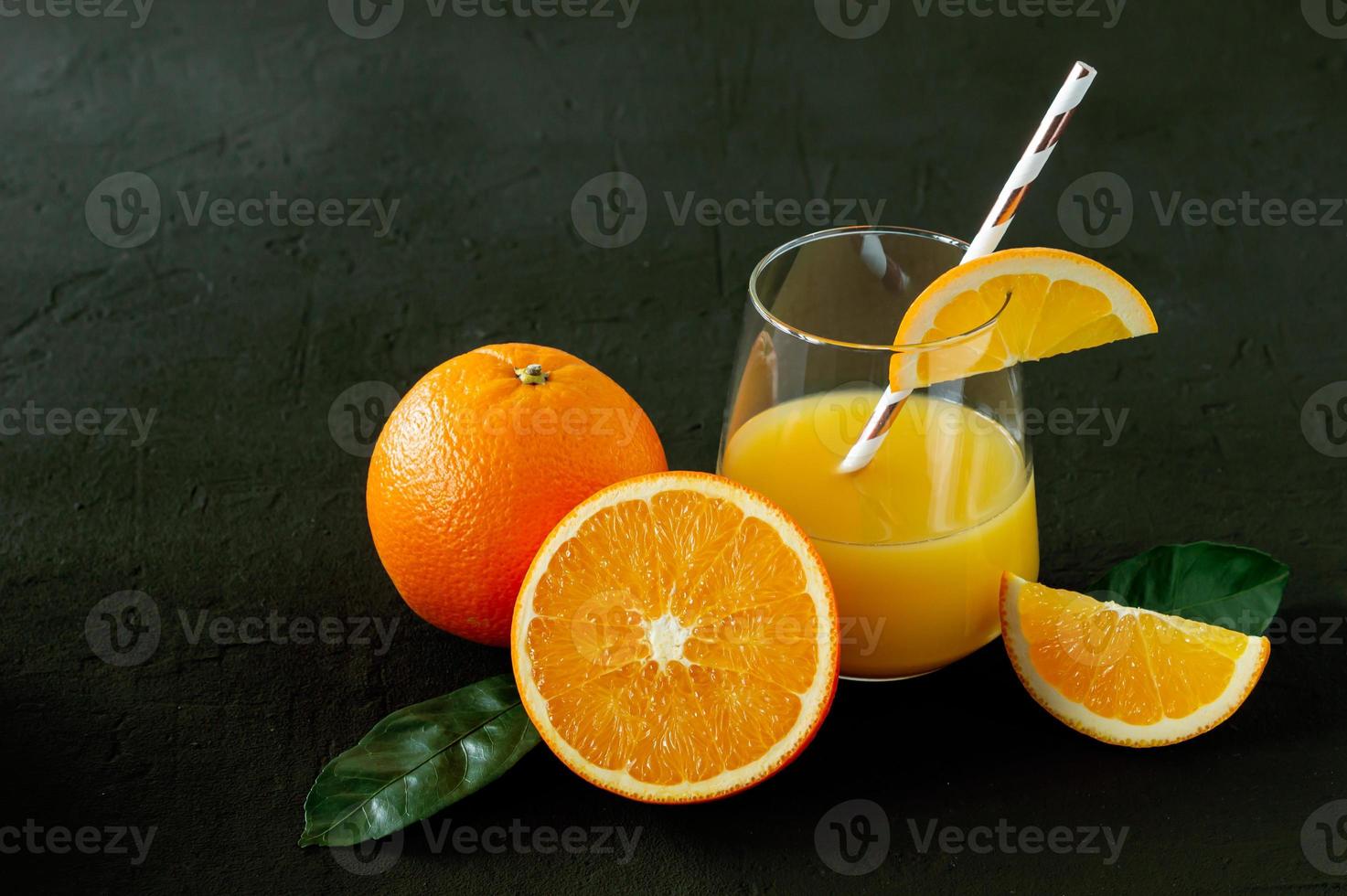 Glas frisch gepresster Orangensaft mit frischen Früchten auf schwarzem Hintergrund foto