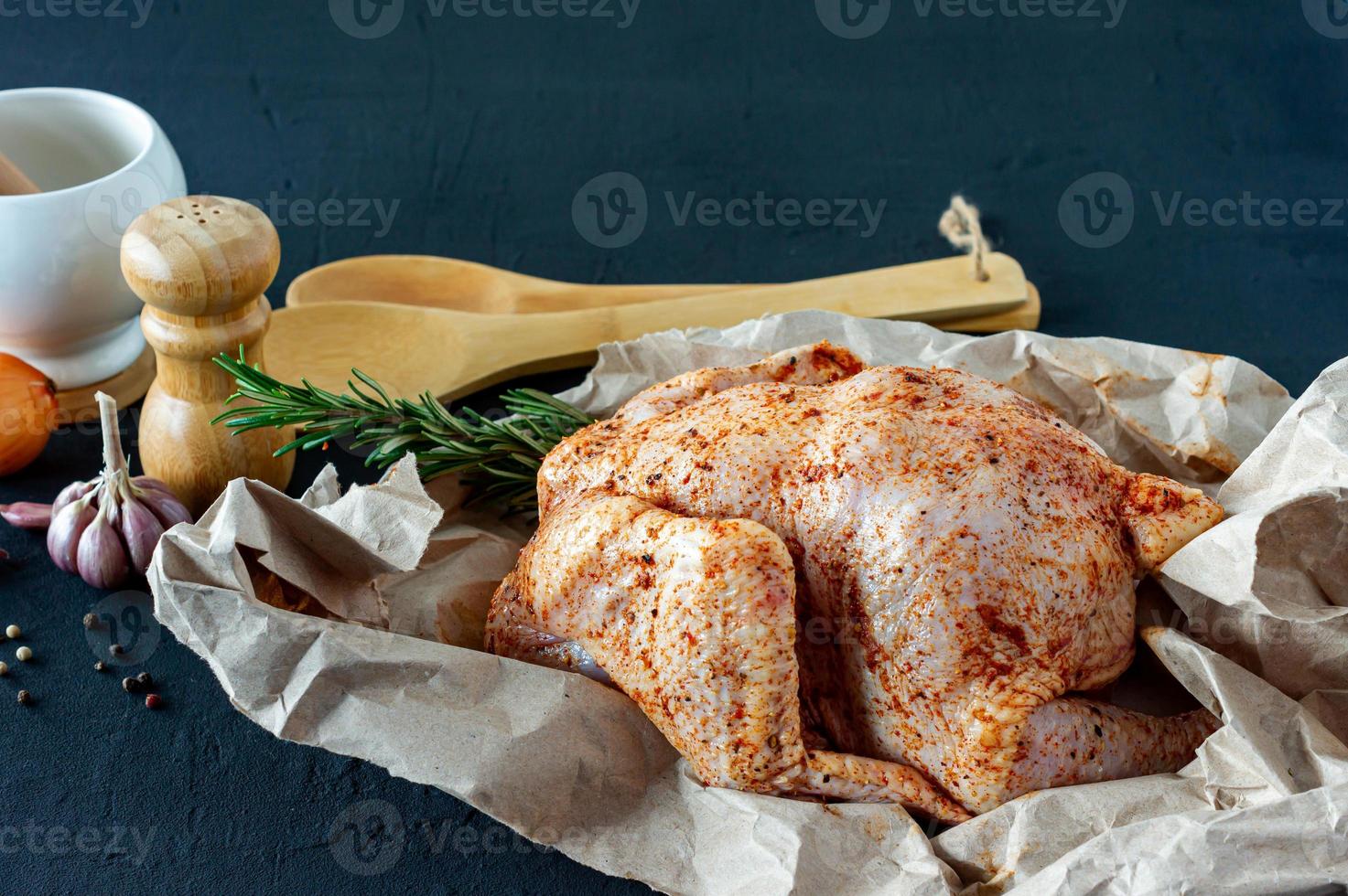 frisches rohes Hühnchen auf Backpapier und Gewürzen zum Kochen. foto