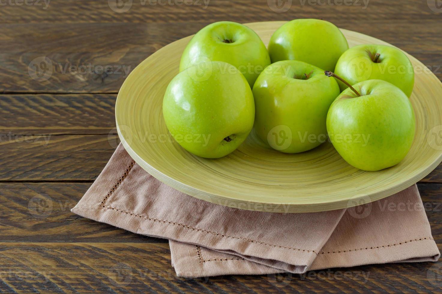 Bio-Oma-Smith-Äpfel auf einem Teller auf Holztisch. foto