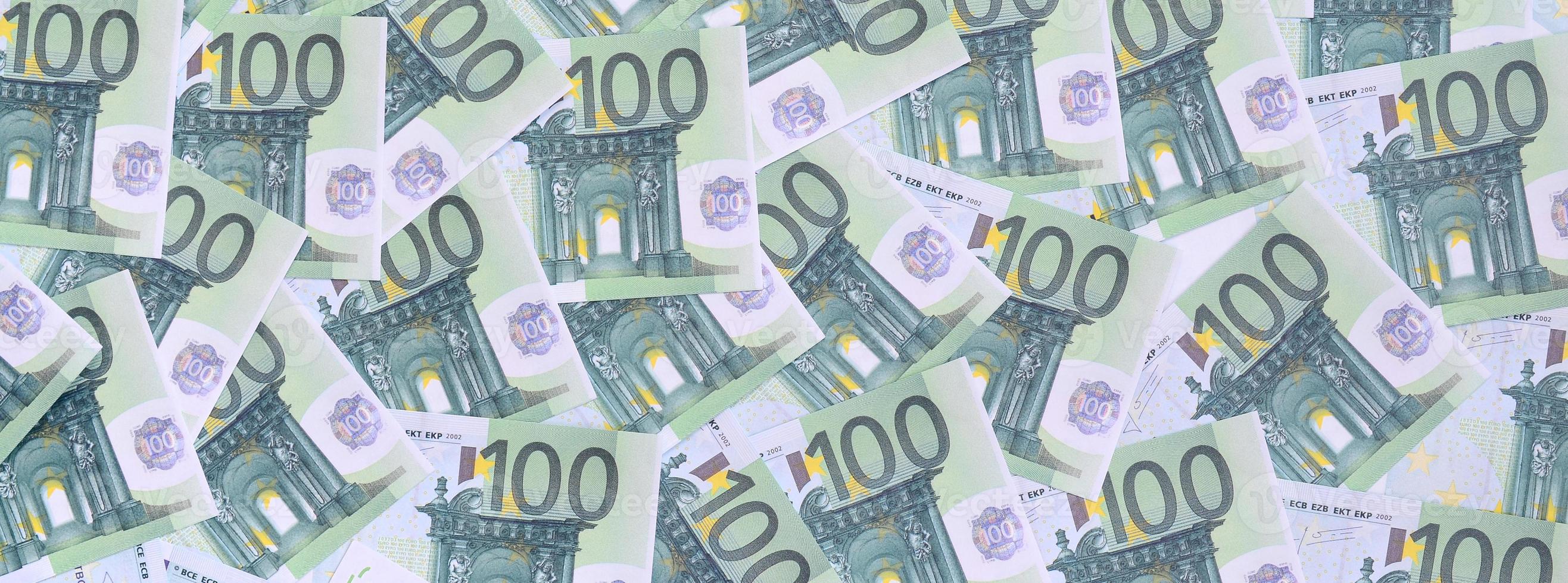Hintergrundmuster einer Reihe grüner Geldstückelungen von 100 Euro. viel Geld bildet einen unendlichen Haufen foto