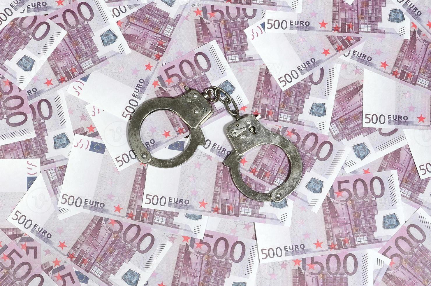 Handschellen auf fünfhundert Euro Hintergrund. Finanzkriminalität, schmutziges Geld und Korruptionskonzept - 500 Geldscheine und schmutzige Stahlhandschellen foto