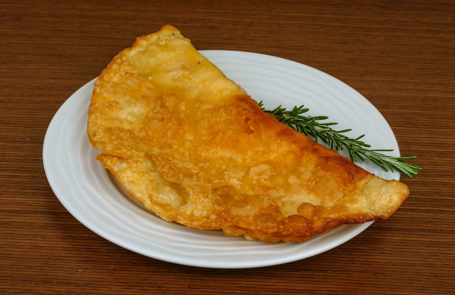 Fleisch-Cheburek auf dem Teller und Holzhintergrund foto