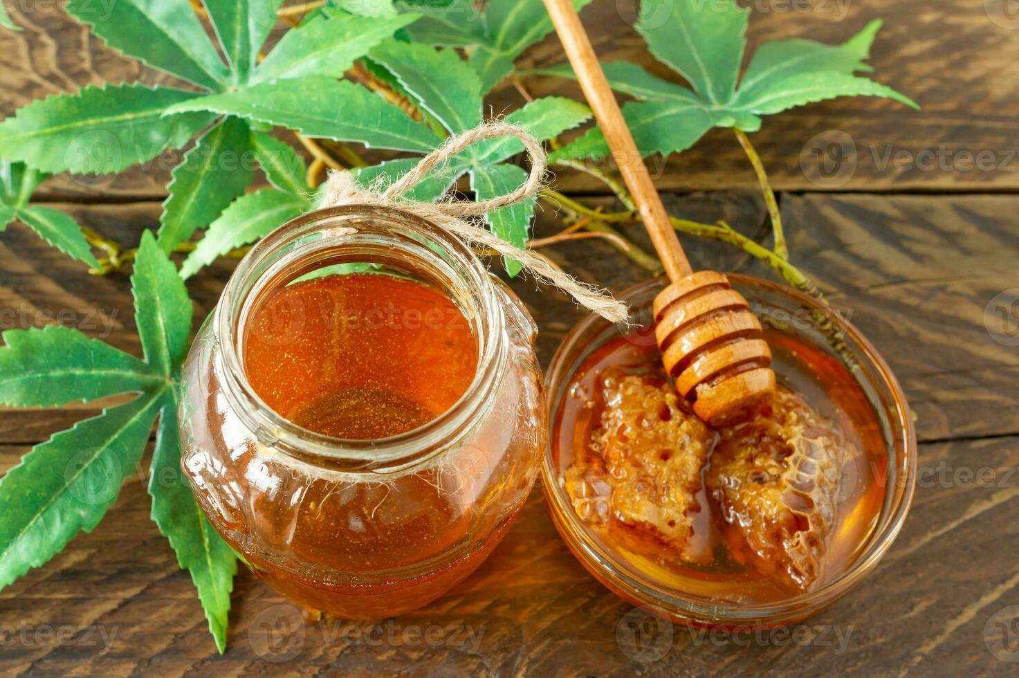 Cannabisblätter, Marihuana und frischer reiner Bio-Honig im Glasgefäß auf Holztischhintergrund. honig cbd konzept. foto
