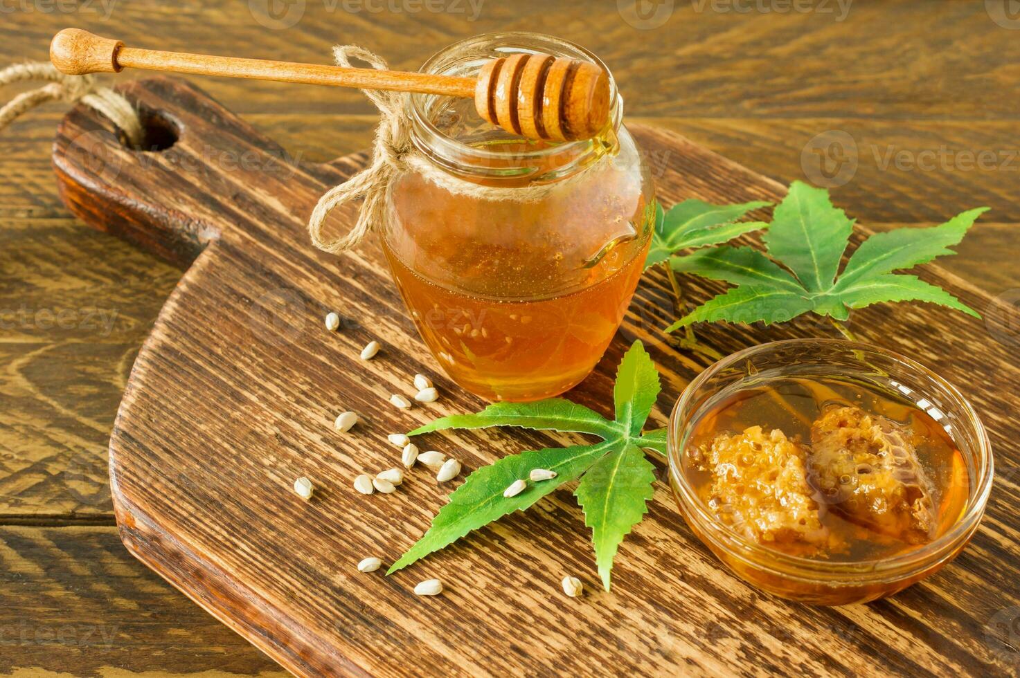 Cannabishonig in einer Schüssel mit Holz tiefer, Hanfblätter und Samen auf Holztisch foto