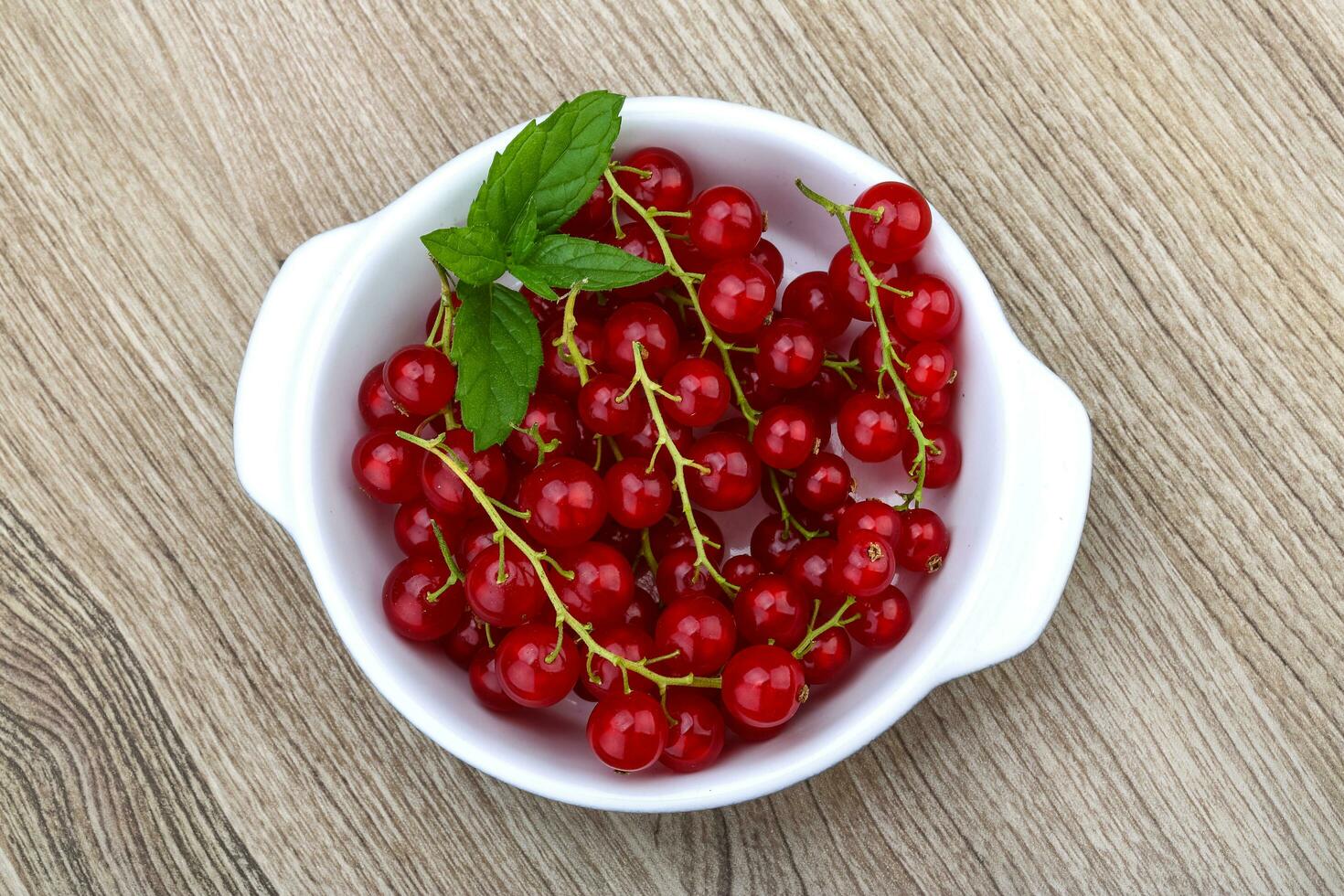 Rote Johannisbeeren in einer Schüssel auf Holzhintergrund foto