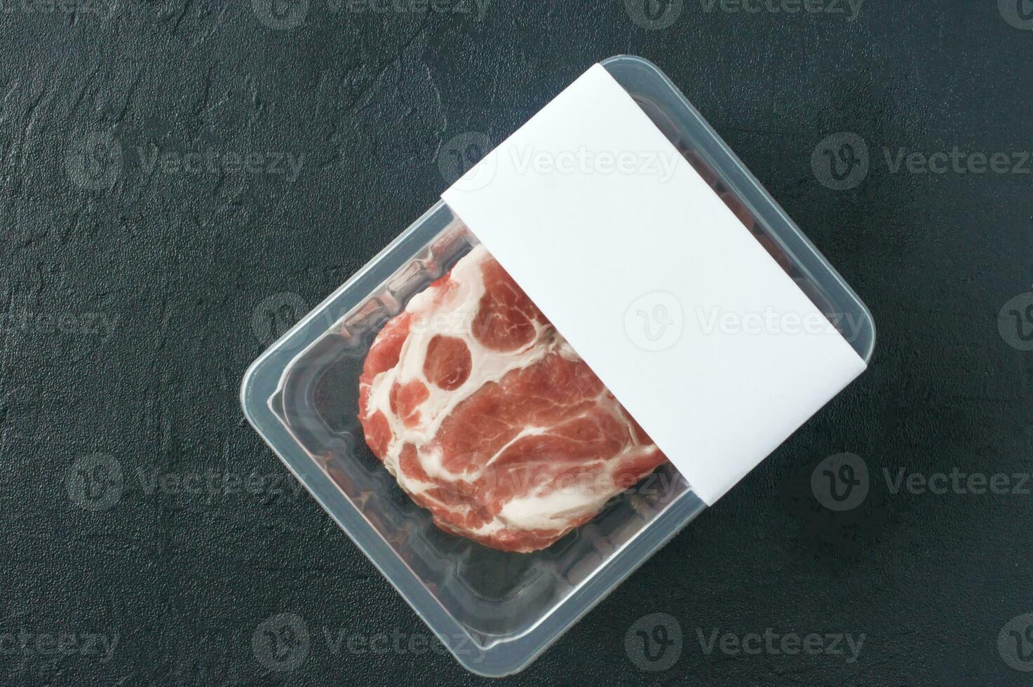 rohes marmoriertes Schweinesteak in Vakuumverpackung auf schwarzem Hintergrund, Draufsicht, Logo-Attrappe für Design foto