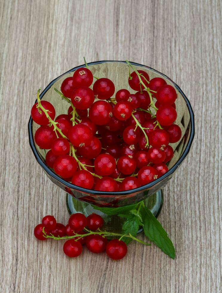 rote Johannisbeere in einer Schüssel auf hölzernem Hintergrund foto