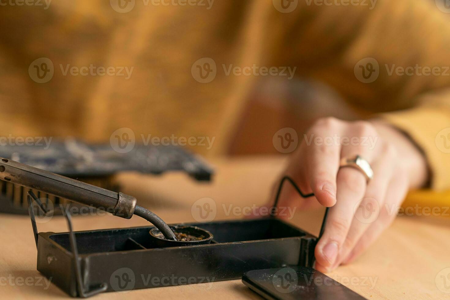 Ein junger Mann lötet einen ausgebrannten Mikroschaltkreis mit einem Lötkolben foto