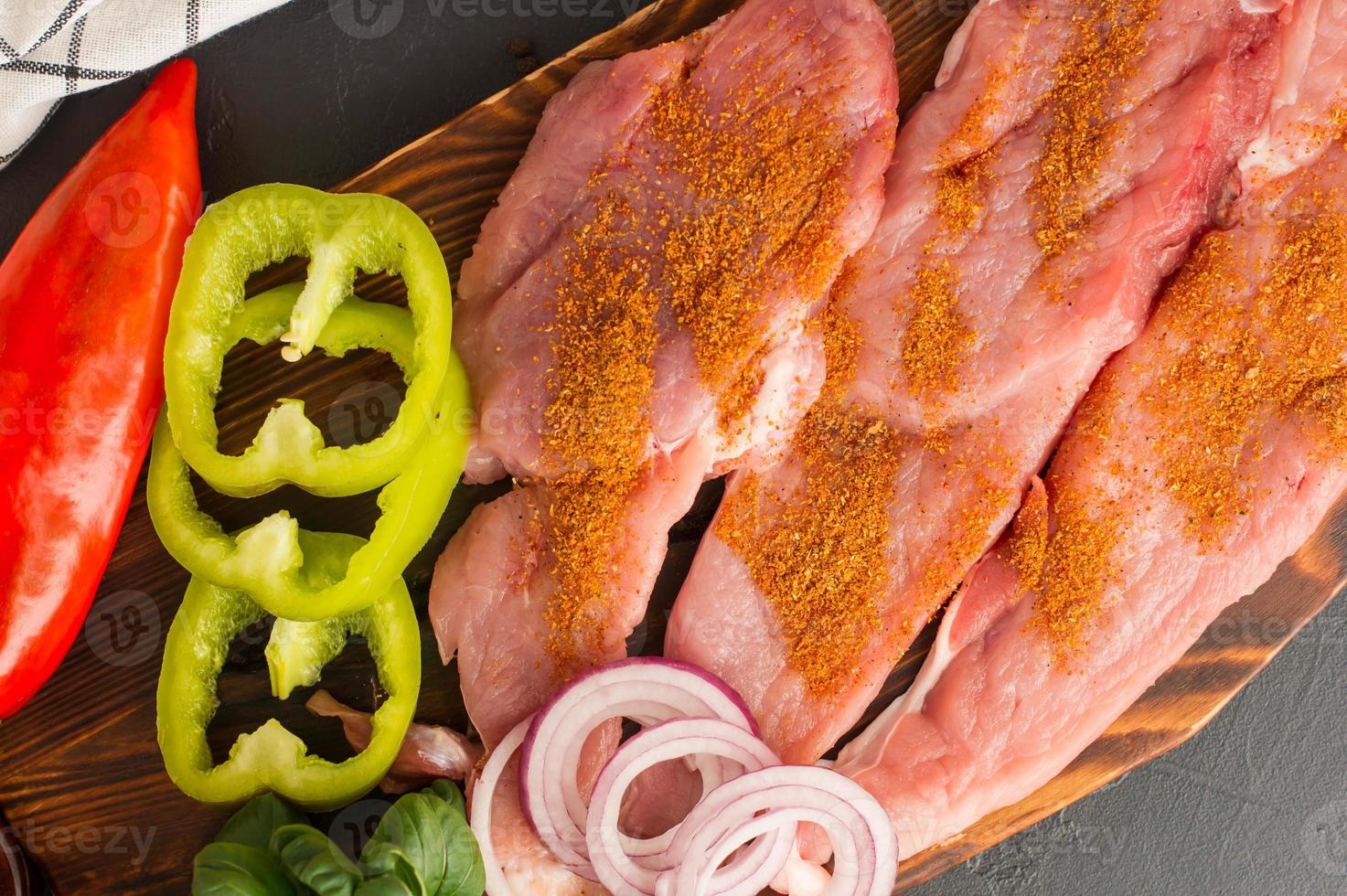 zubereitet zum Backen frische Koteletts aus ausgewähltem Fleisch mit Paprika, Zwiebeln auf dem Küchenbrett. Ansicht von oben. engen Winkel. foto