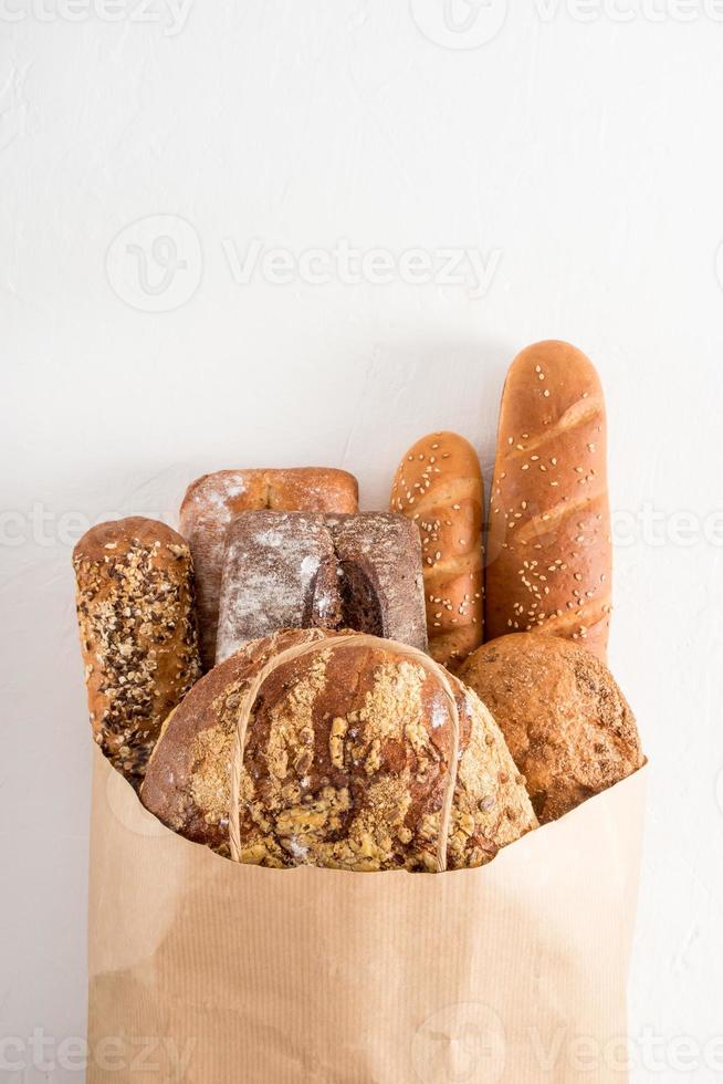 eine volle Tüte frisch gebackenes Brot in einer Bäckerei auf weißem Hintergrund. Konzept von Zero Waste, Öko-Shopping und Lieferung. vertikale flache Ansicht. foto