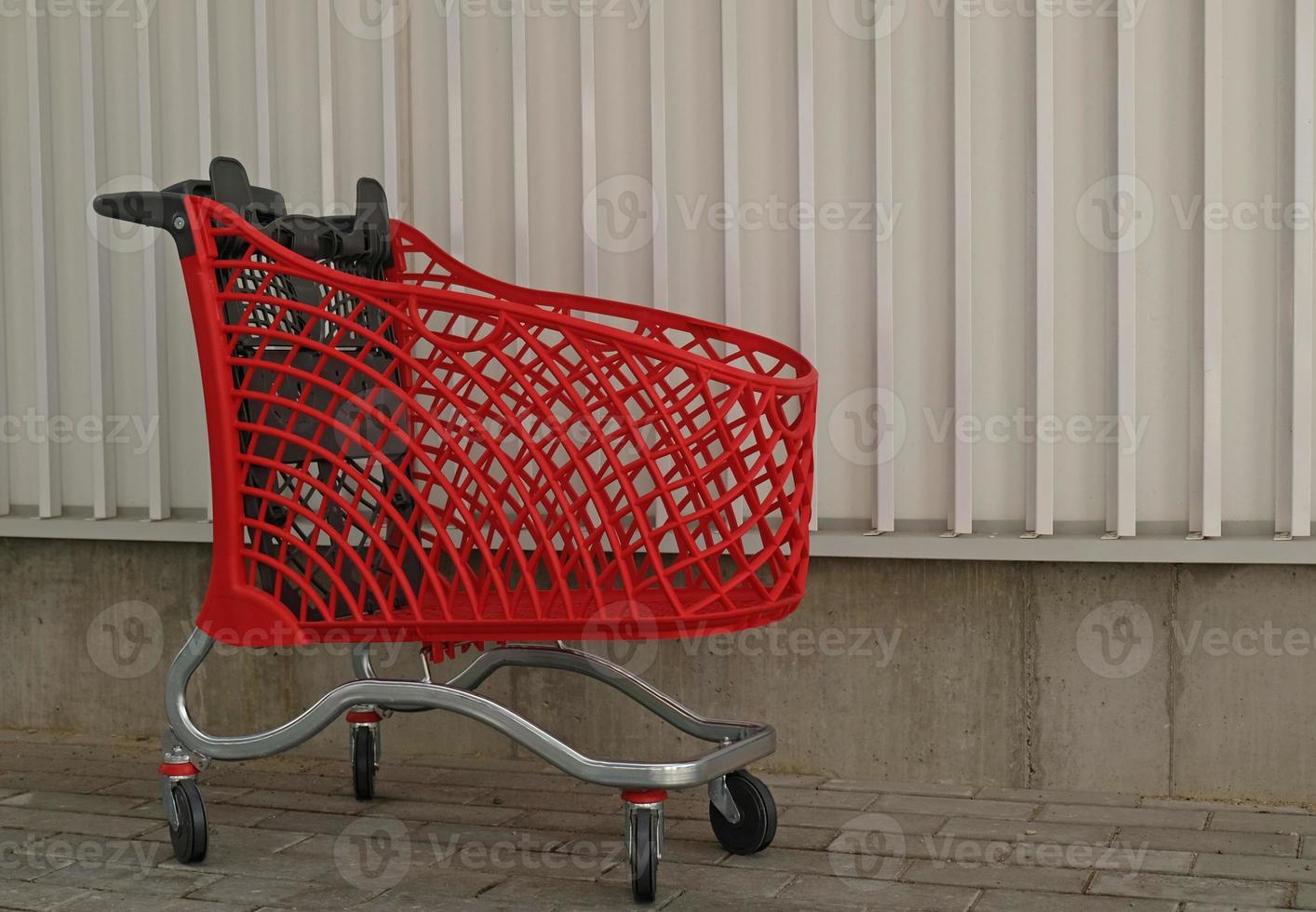 leeres rotes einkaufen auf industriewandhintergrund. Einkaufswagen im Supermarkt. verkauf, rabatt, shopaholismus, schwarzer freitag, wirtschaftskonzept. Trend der Konsumgesellschaft. Online-Shopping-Konzept. foto