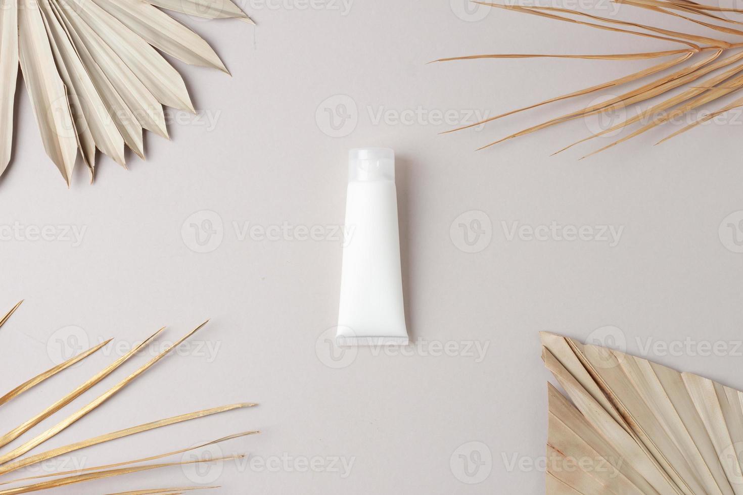 weiße Tube kosmetische Creme mit Palmblatt auf grauem Hintergrund. flach liegen foto
