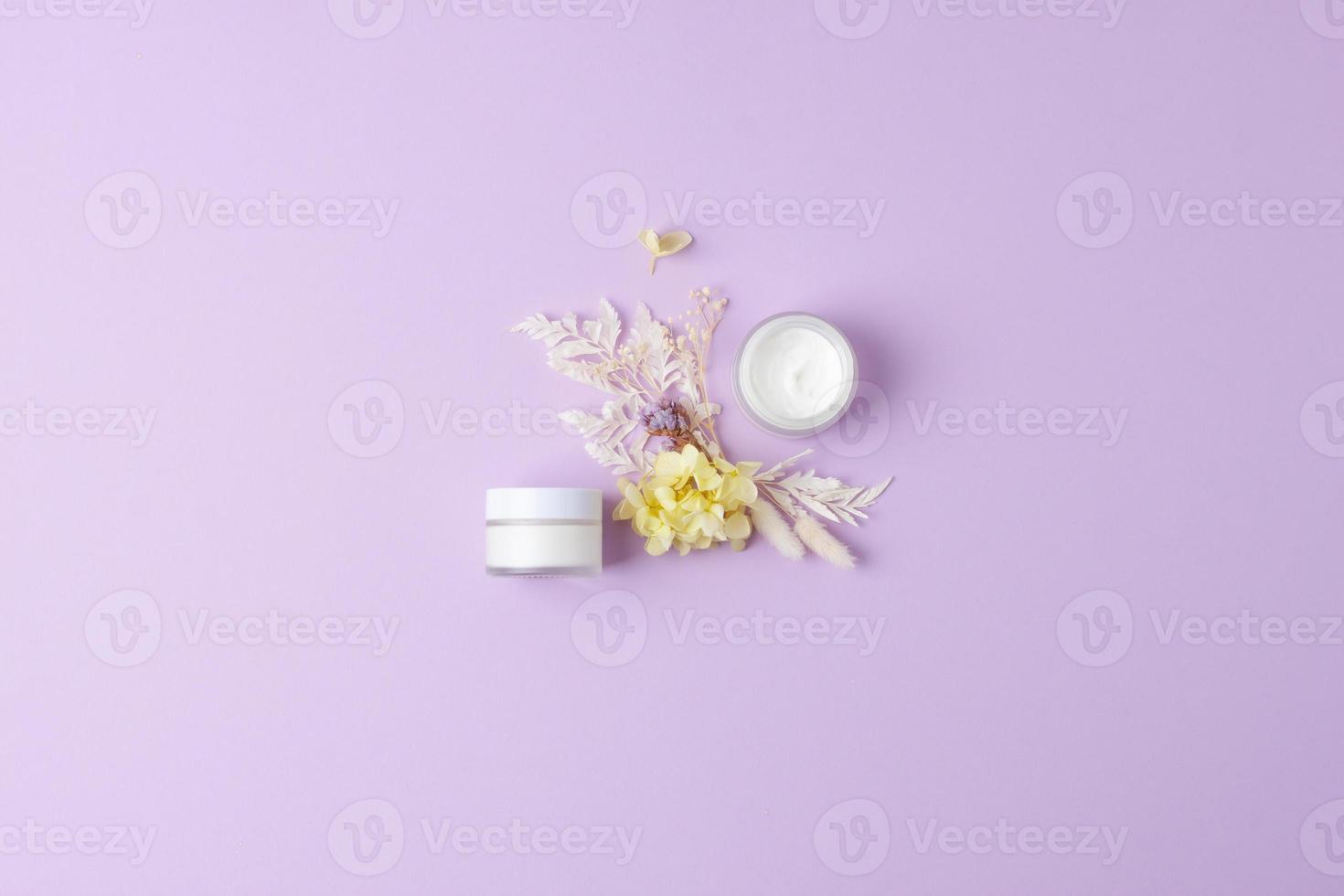 gläser kosmetische creme mit blumen auf rosafarbenem hintergrund. flach liegend, kopierraum foto