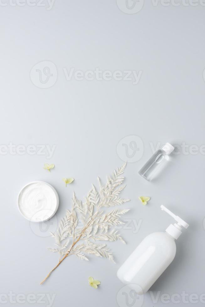 kosmetische hautpflegeprodukte mit blumen auf grauem hintergrund. flach liegend, kopierraum foto
