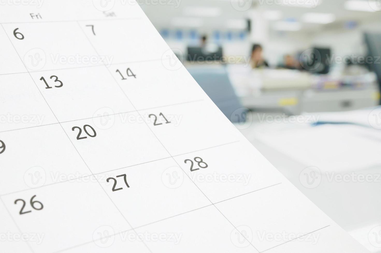Schließen Sie herauf weißen Papiertischkalender auf Tabelle mit unscharfem Büroinnenhintergrund foto
