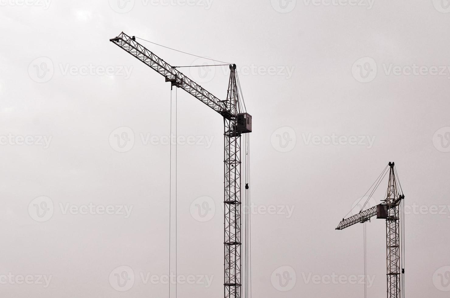 abstrakter industrieller Hintergrund mit Bauturmkranen über klarem blauem Himmel. Baustelle. Gebäude im Bau Konzept. Retro-Ton foto