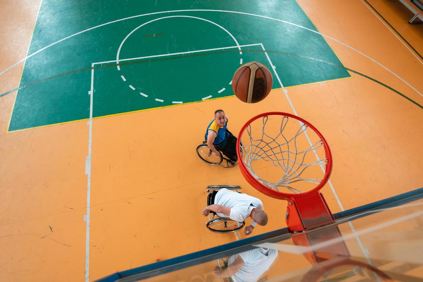 behinderte kriegs- oder arbeitsveteranen gemischte rassen- und alters-basketballteams in rollstühlen, die ein trainingsspiel in einer sportturnhalle spielen. Rehabilitations- und Inklusionskonzept für behinderte Menschen. foto