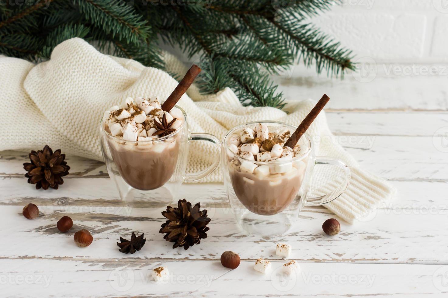 Zwei transparente Tassen mit doppeltem Boden mit heißer Schokolade und Marshmallow auf weißem Holzhintergrund. das konzept neujahrsferien. foto