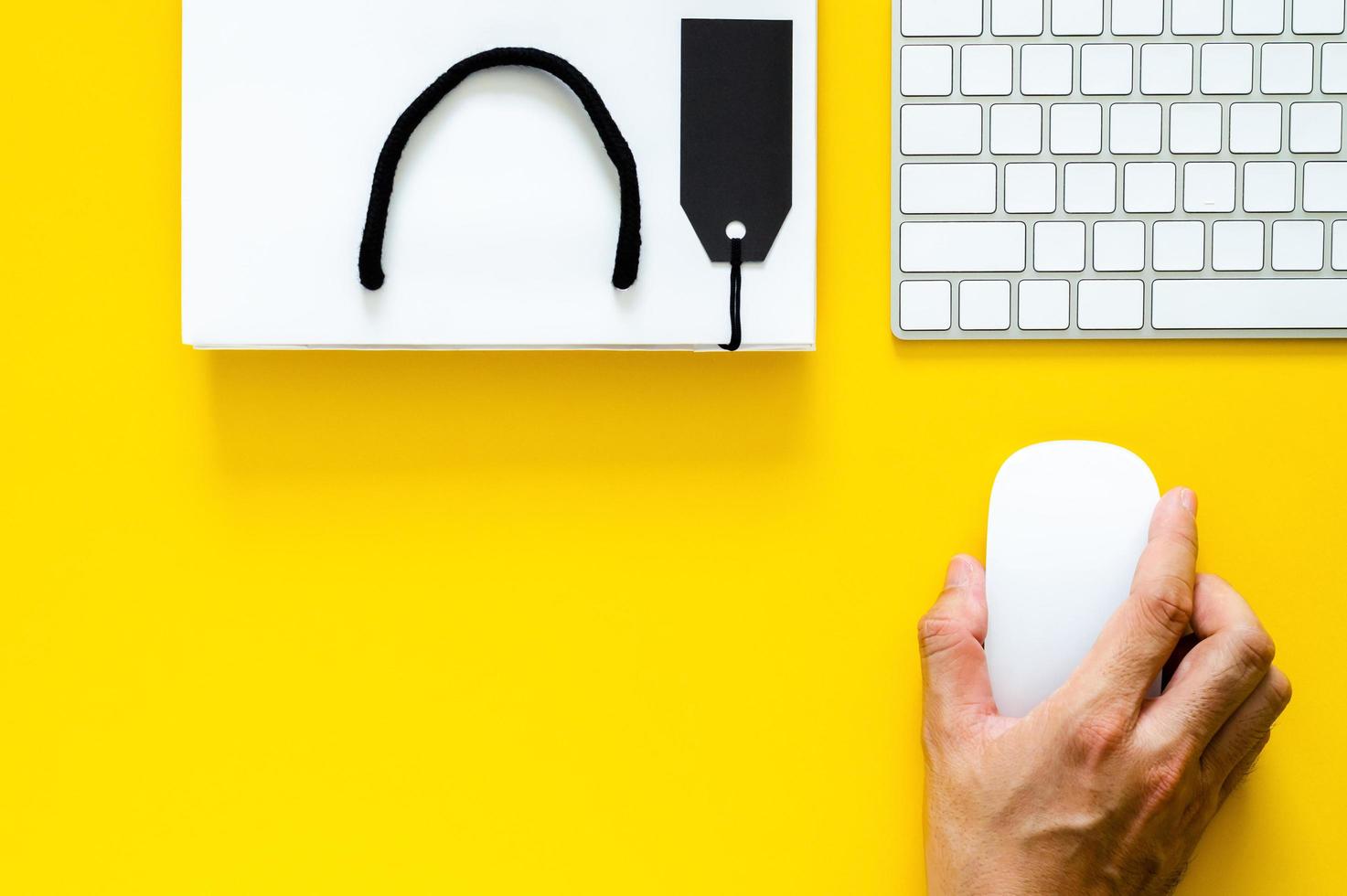 hand, die drahtlose maus mit tastatur für online-einkäufe auf gelbem hintergrund hält. cyber montag und schwarzer freitag konzept. foto