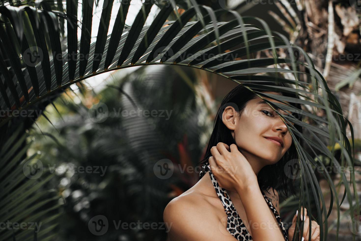 Außenaufnahme eines selbstbewussten Mädchens im exotischen Resort. lächelndes weibliches Modell, das im Regenwald aufwirft. foto