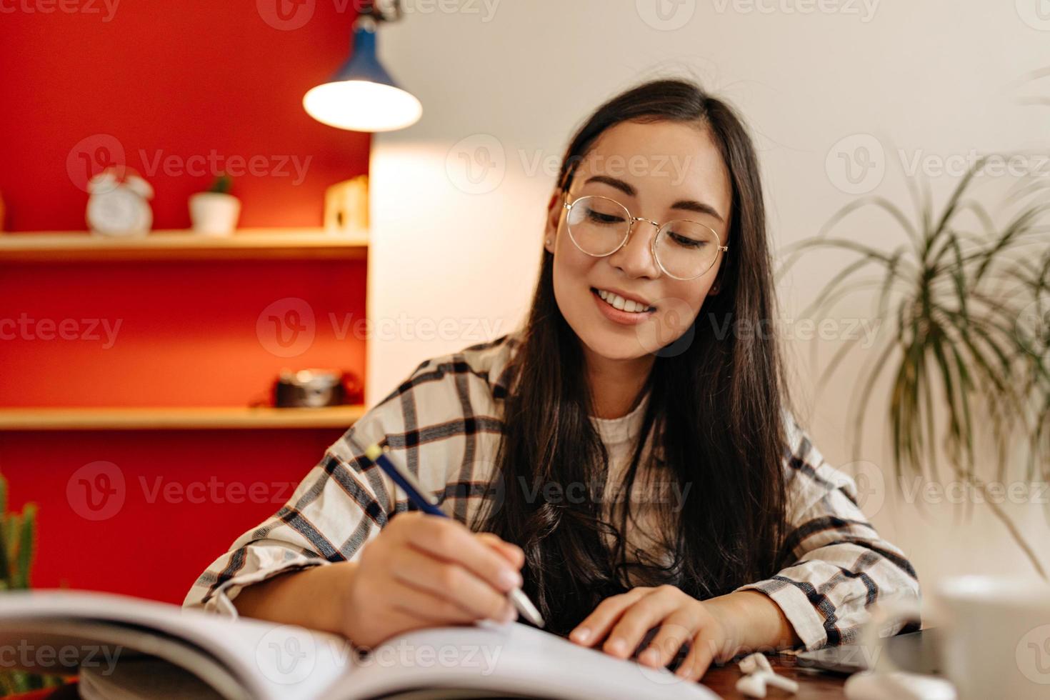 Studentin mit Brille liest abstrakt mit Interesse und unterstreicht wichtige Wörter foto