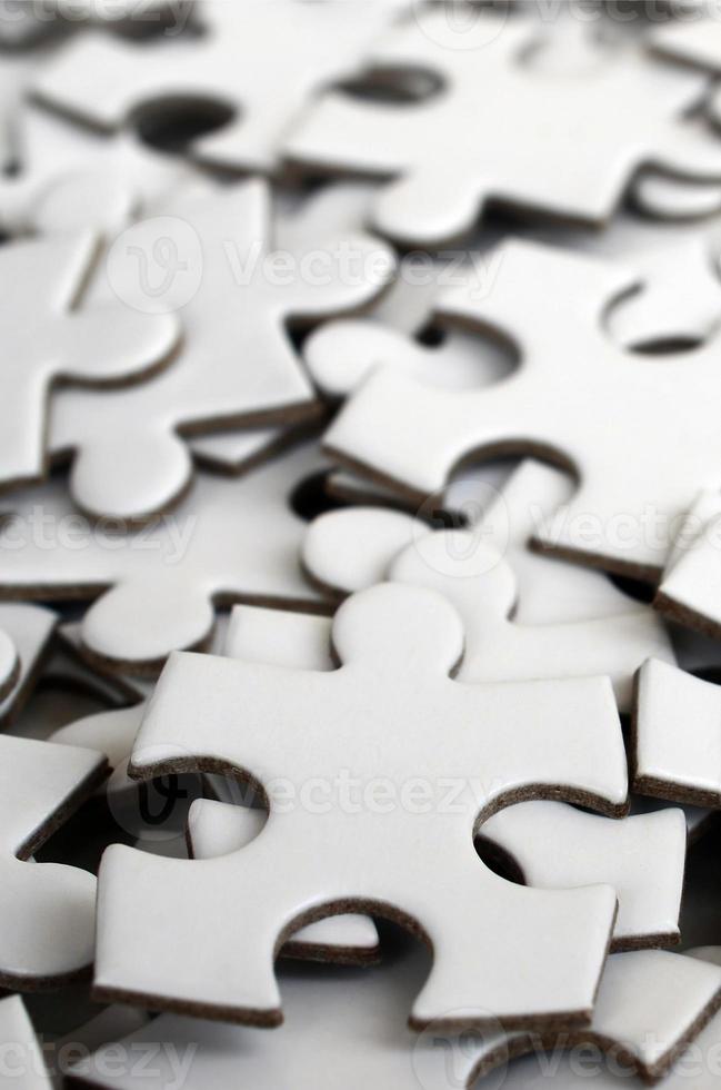 Nahaufnahme eines Stapels unvollständiger Elemente eines weißen Puzzles. eine große Anzahl rechteckiger Stücke aus einem großen weißen Mosaik foto