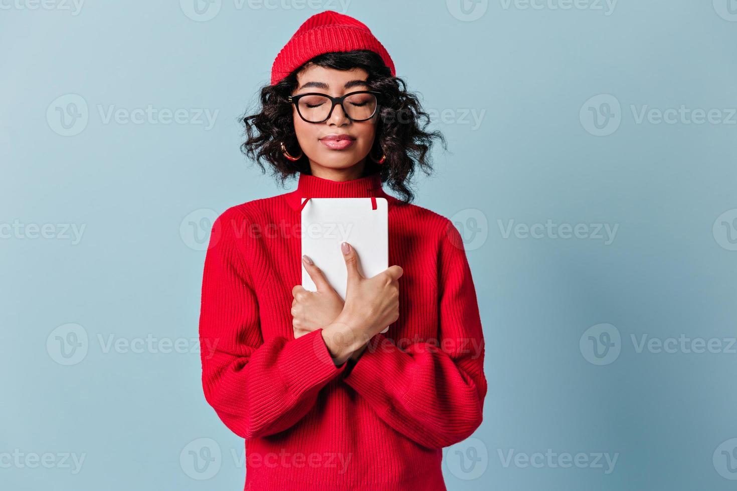 Vorderansicht des Mischlingsmädchens mit geschlossenen Augen. attraktive junge Frau mit Brille und roter Kleidung s foto