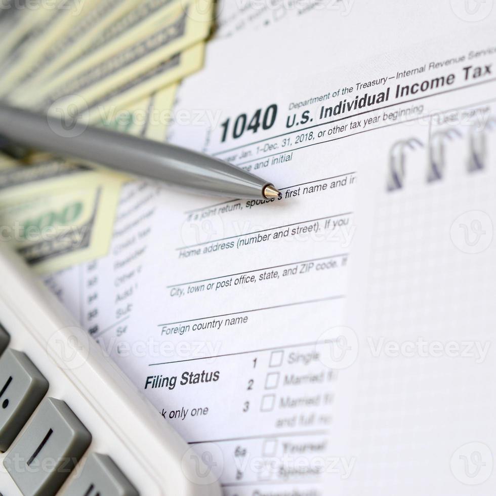 Der Stift, das Notizbuch, der Taschenrechner und die Dollarscheine befinden sich auf dem Steuerformular 1040 US-Einzeleinkommensteuererklärung. die Zeit, Steuern zu zahlen foto