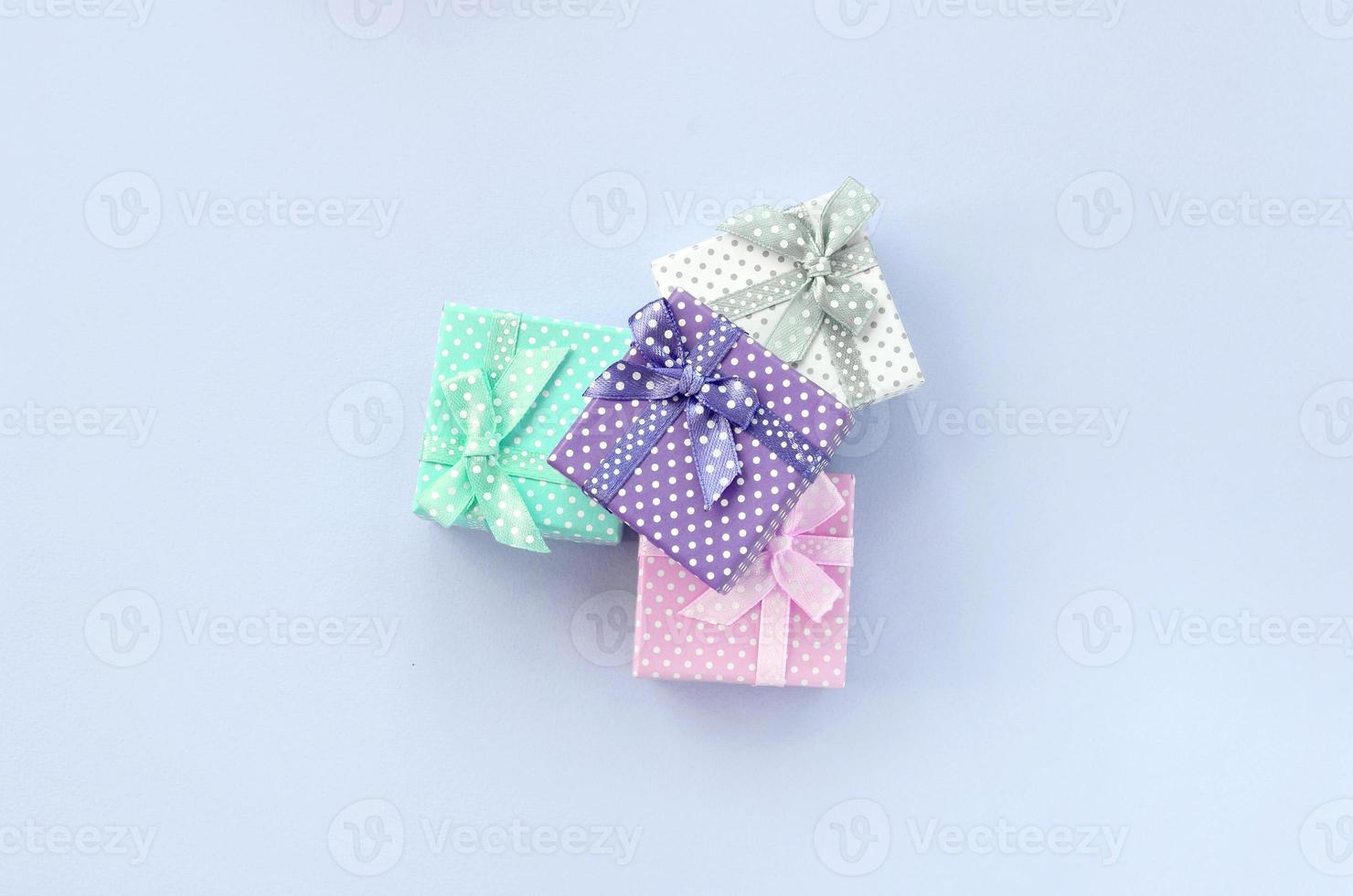 Haufen von kleinen farbigen Geschenkboxen mit Bändern liegt auf violettem Hintergrund foto