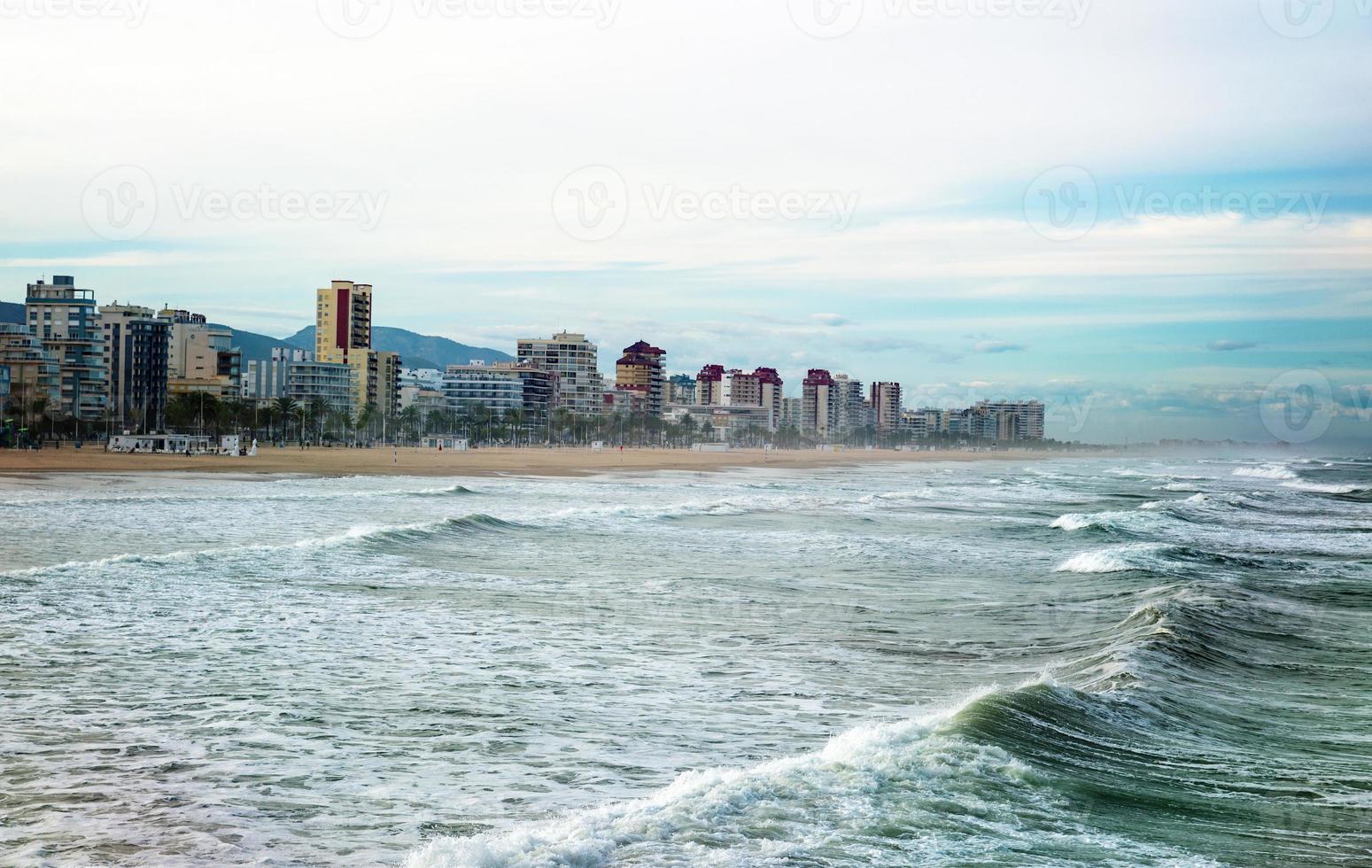 schöne aussicht auf den strand der küstenstadt von der seite des rauen meeres mit bergen im hintergrund foto