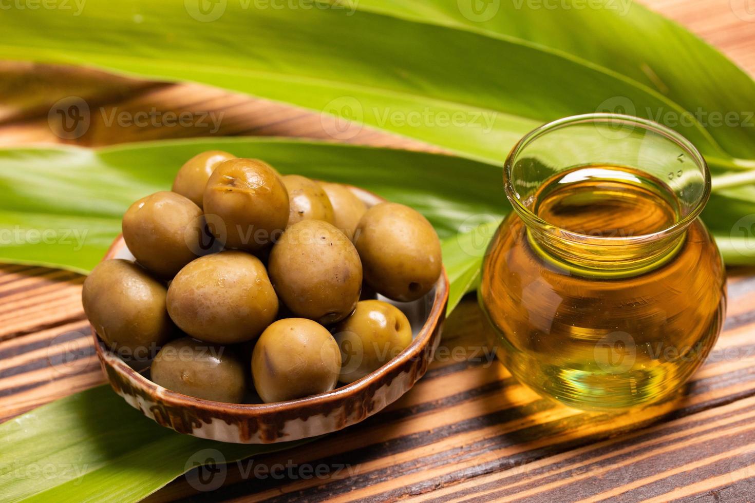 olivenöl mit olivenfrüchten auf holzhintergrund foto