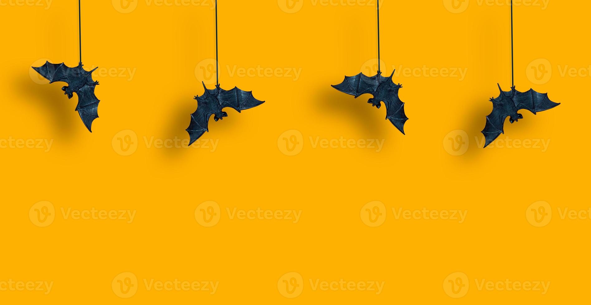 horizontales Muster. Schwarze Fledermäuse in Reihe sind mit ausgebreiteten Flügeln auf gelb-orangefarbenem Hintergrund aufgehängt. heiligen. Platz kopieren foto