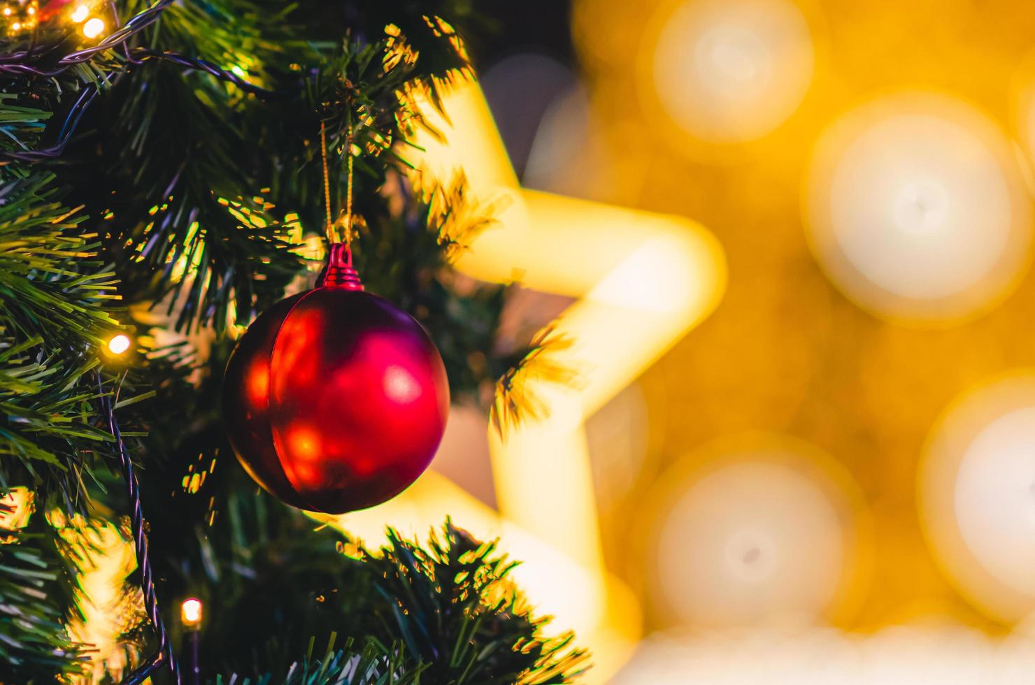 rote Kugel, die am Weihnachtsbaum mit buntem Hintergrund hängt. foto