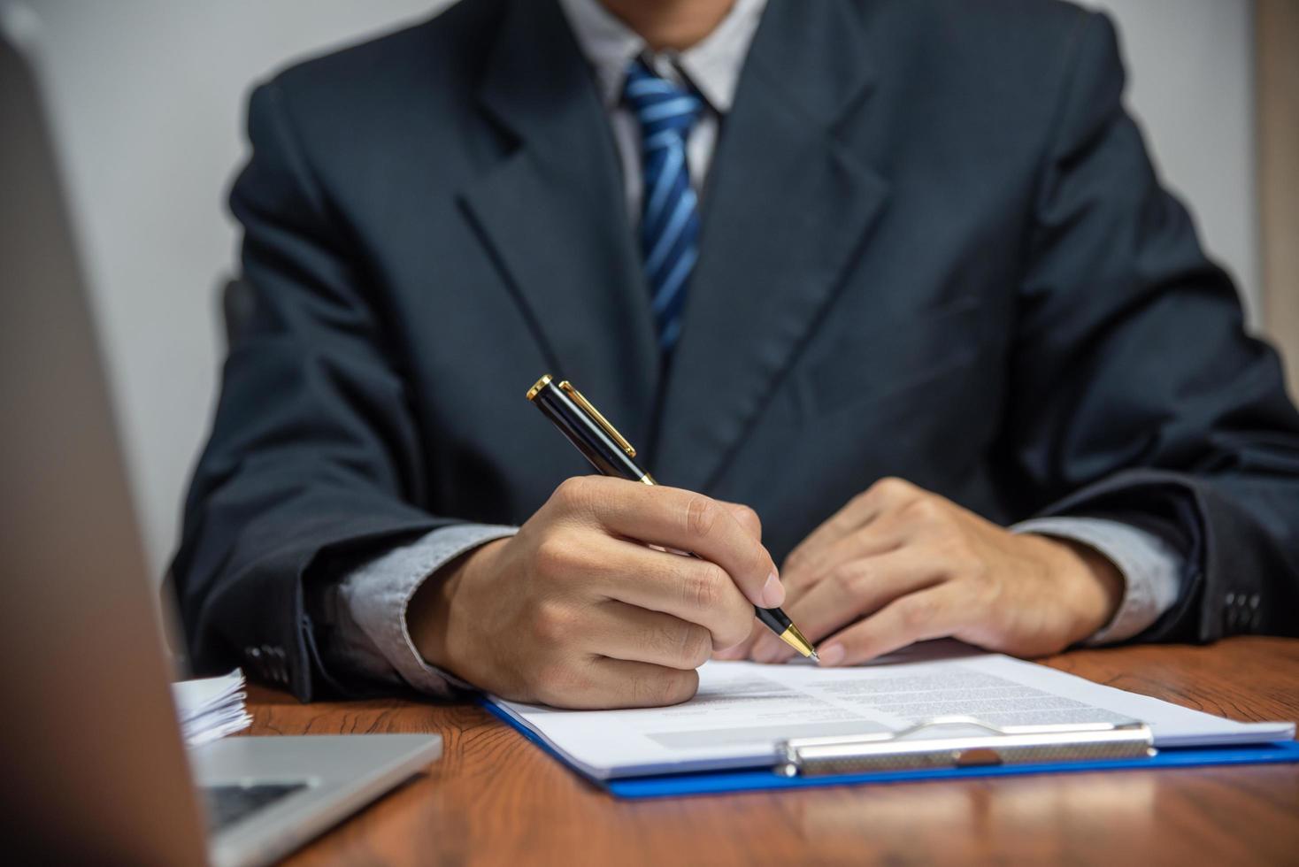 Hand mit Stift schreiben Papierkram Geschäftsdokument Finanzinvestition oder Unterschrift Vertrag Job und Versicherung auf dem Schreibtisch. foto