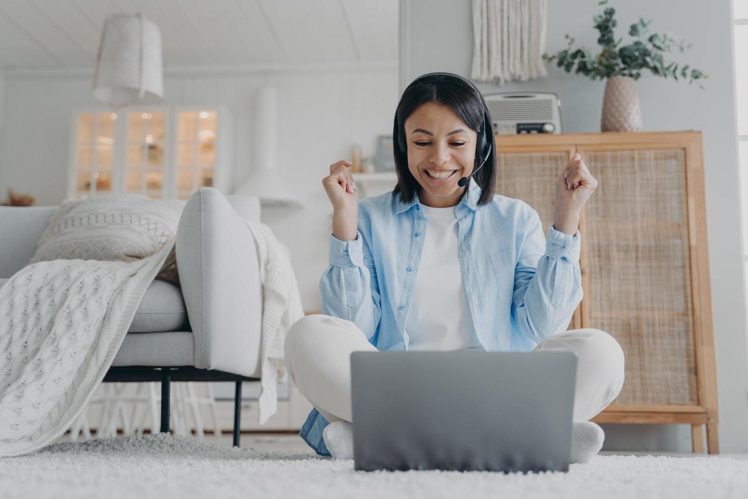 freundliche Trainerin im Headset, die online am Laptop arbeitet, führt ein Webinar zu Hause durch. E-Learning foto