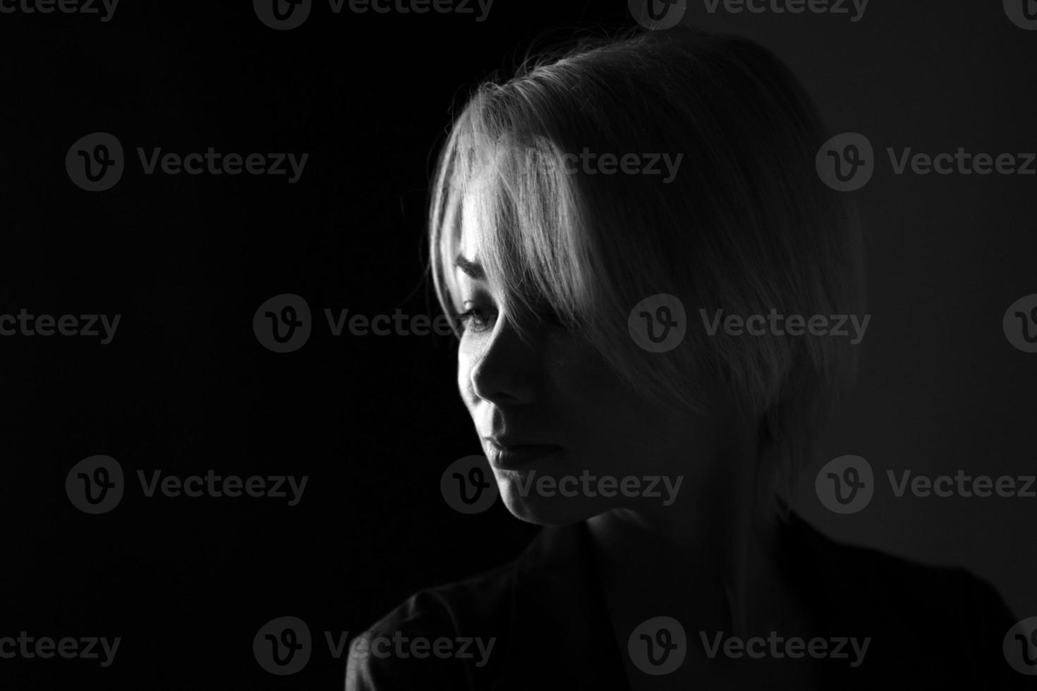 Porträt einer jungen traurigen Frau, die wegschaut, dunkles Schwarz-Weiß-Foto foto