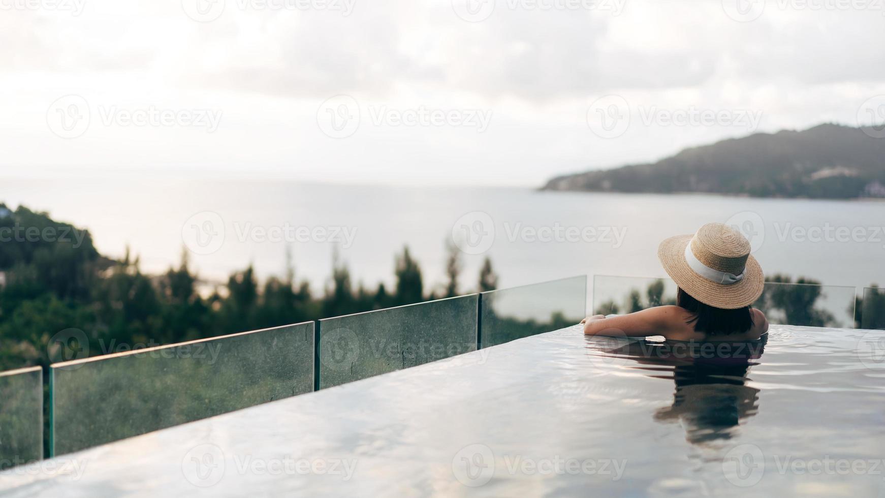 Rückansicht der asiatischen Frau Entspannen Sie sich im Poolresort mit Meerblick im Freien foto