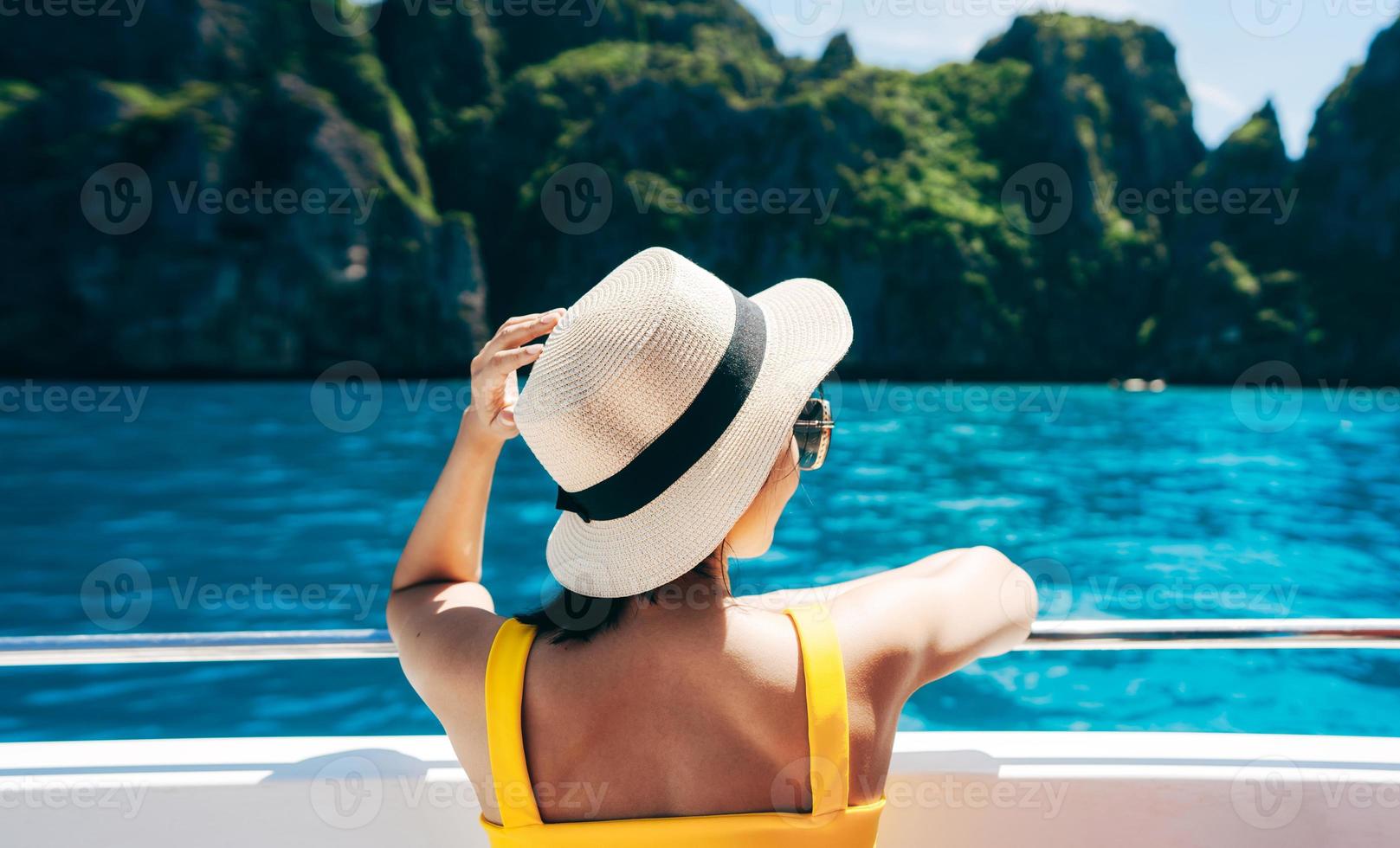 rückansicht der erwachsenen reisenden frau entspannen sie sich auf dem segelboot mit sommerinsel und meer foto