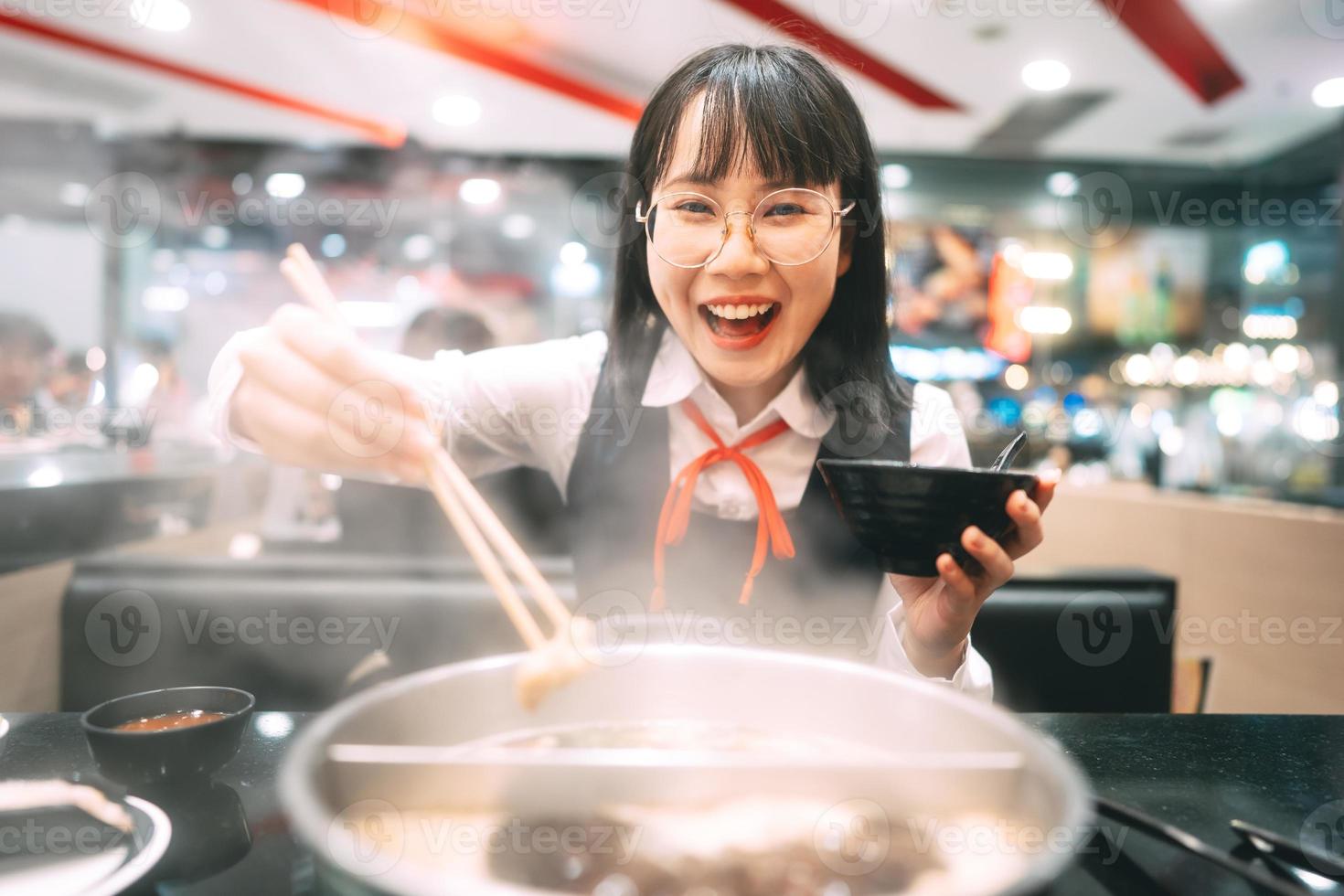 glückliche junge asiatin japanischer thailändischer student, der shabu japan sukiyaki restaurant isst. foto